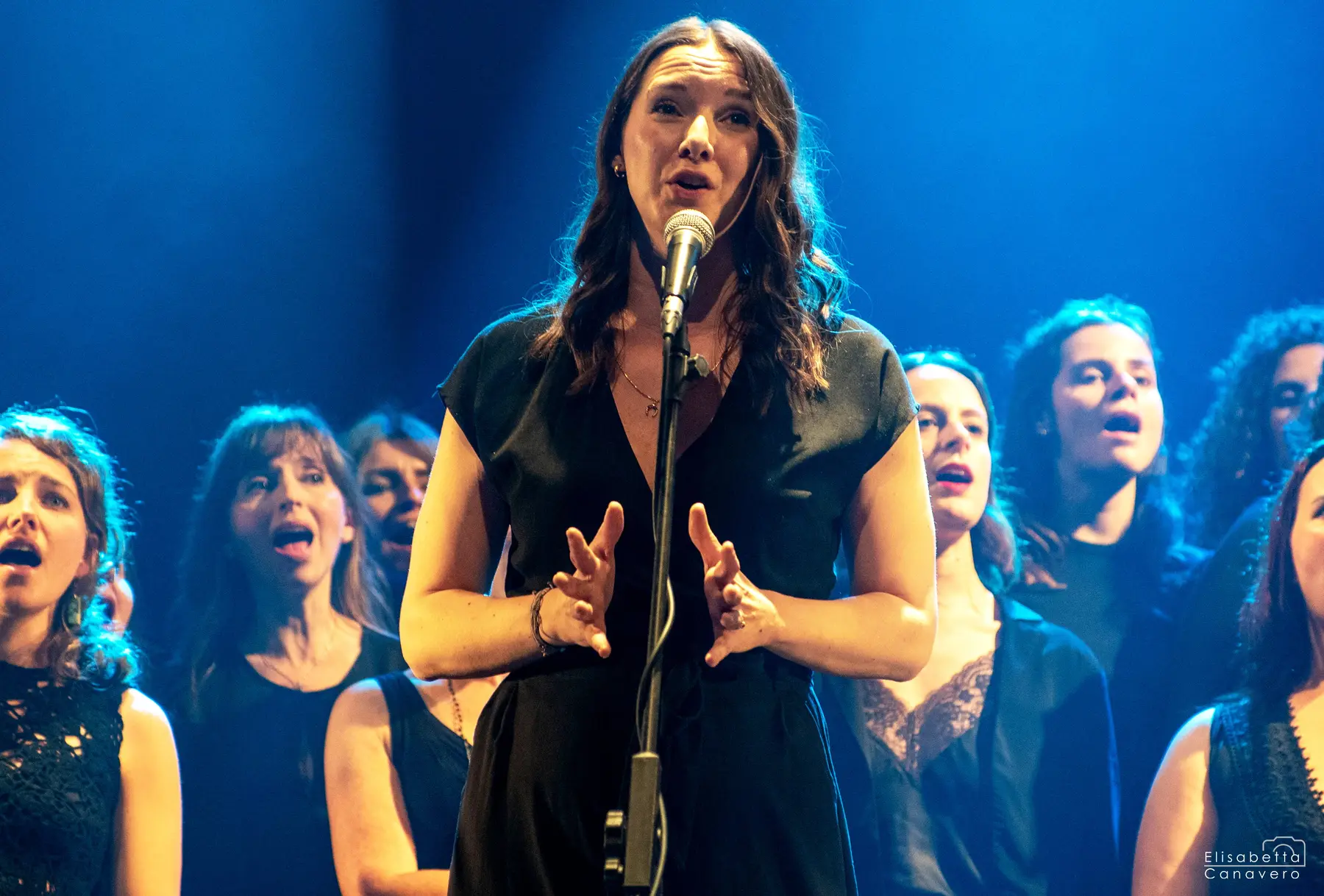 Una cantante si esibisce davanti al coro sotto luci blu